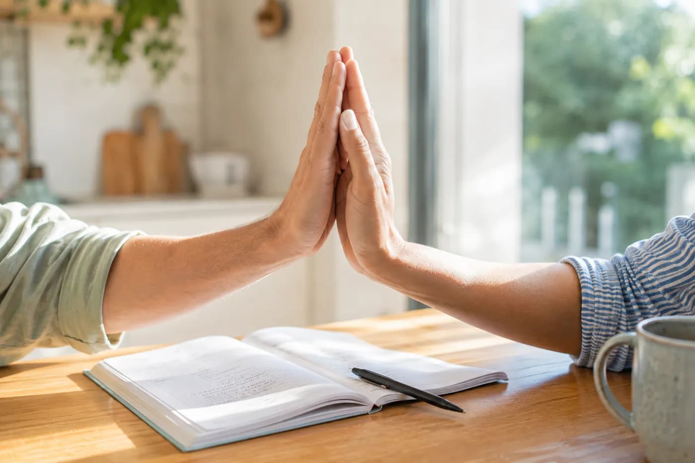 Two adults high-fiving over an open exercise book